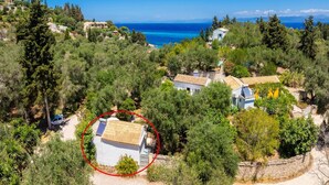 Propiedad costera con varias construcciones rodeadas de vegetación exuberante y una vista despejada del mar.