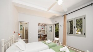 Habitación de hotel con dos camas, ventilador de techo y vista al exterior a través de una ventana.