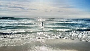 Ein Strand mit Wellen und einer Person, die im Wasser steht.