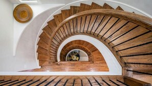 Eine hölzerne Wendeltreppe mit kreisförmigem Design, die zu einer oberen Etage führt.