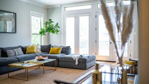 Ein modernes Wohnzimmer mit einem Ecksofa, einem Couchtisch und einem großen Fenster, das für natürliches Licht sorgt.