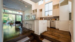A spacious kitchen with white cabinetry, a large window, and a view of the outdoors.