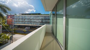 Un balcon donnant sur un immeuble moderne et une rue en contrebas.