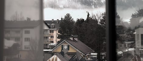 Vista de montañas a través de una ventana, con edificios a la vista y cielo despejado.