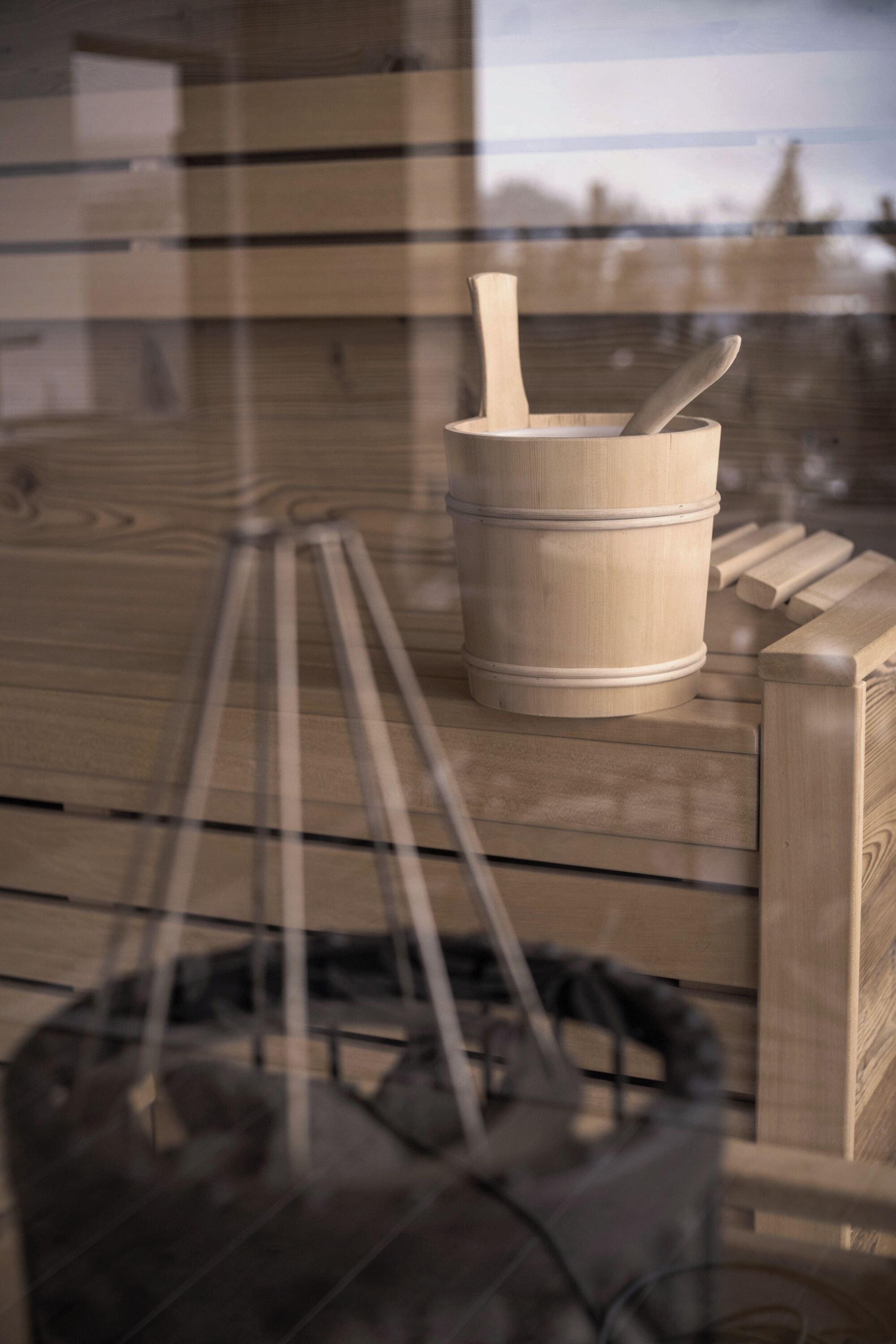 Un sauna en bois, avec un seau en bois et une cuillère en bois posés sur un banc.