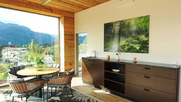 Eine moderne Küche mit großem Fenster, Holzboden und einem Essbereich mit Korbstühlen.