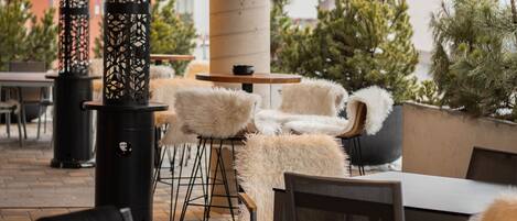 An outdoor seating area with tables and chairs, decorative columns, and potted plants.