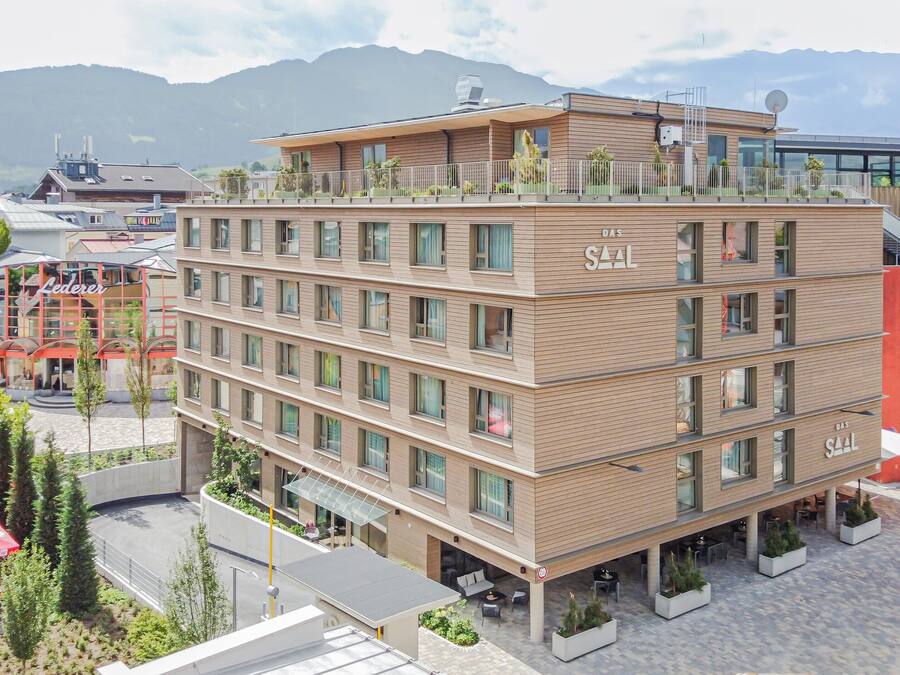A multi-story hotel with a modern design, featuring balconies and outdoor seating areas.