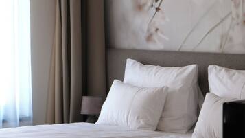 Een net opgemaakt bed met witte lakens, een donker hoofdbord en een wandlamp.