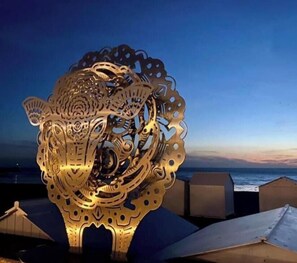 A metallic sculpture with intricate cut-out patterns, set against a twilight sky.