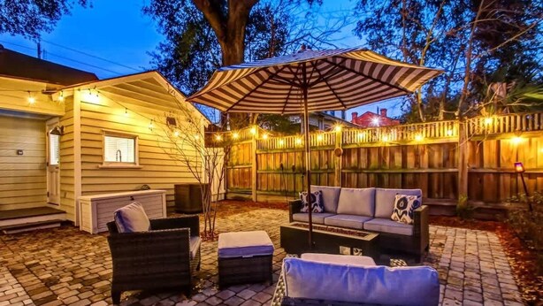 An outdoor patio area with a wooden deck, wicker furniture, and string lights.