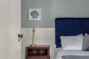 A bedroom with a bed, a nightstand, a framed artwork, and a door. - Hot Tub - Historic District - Next to Forsyth Park (Savannah)
