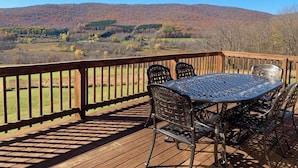 Eine Terrasse mit einem Metalltisch und -stühlen, mit Blick auf eine hügelige Landschaft.