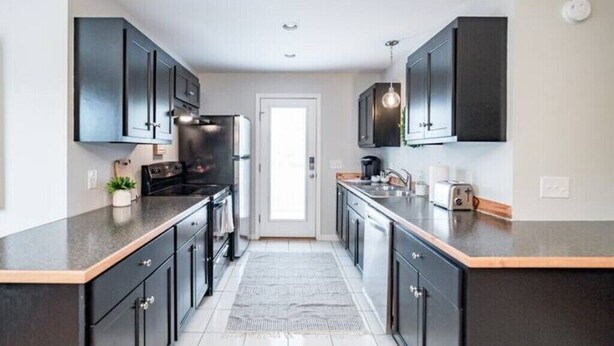 A modern kitchen with dark cabinets, a central island, and a view to the living area.