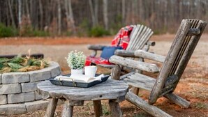 A rustic outdoor seating area with a wooden chair and a small round table.