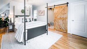 A bedroom with a four-poster bed, a wooden sliding door, and a white door.