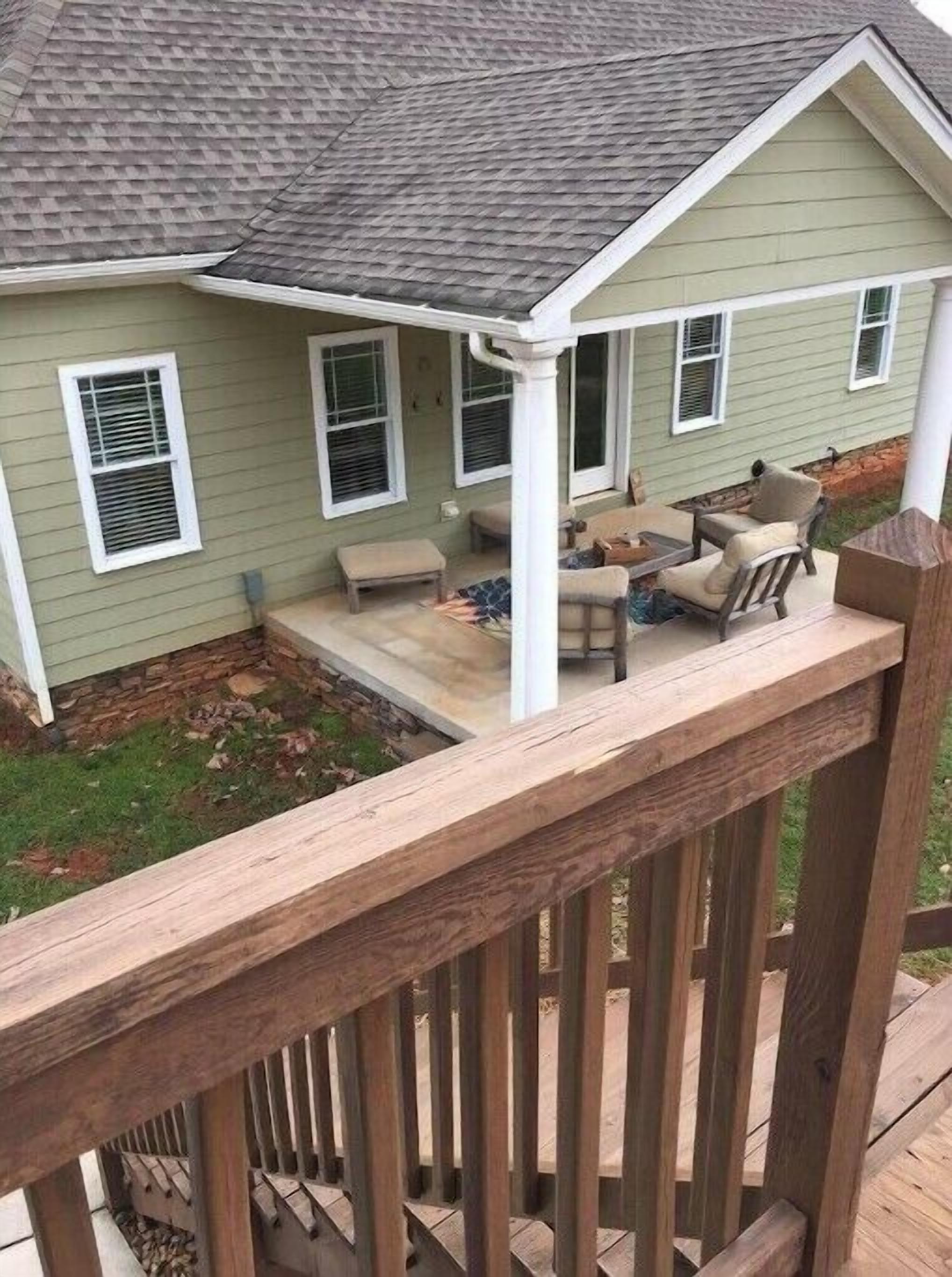 Een huis met een overdekte veranda, een klein zitgedeelte met een tafel en stoelen, en een houten vlonderhek.