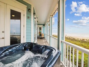 Ein Whirlpool auf einer Holzterrasse mit Blick auf den Strand.