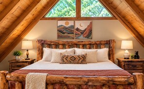 A bedroom with a wooden bed frame, two bedside tables, and a large window.
