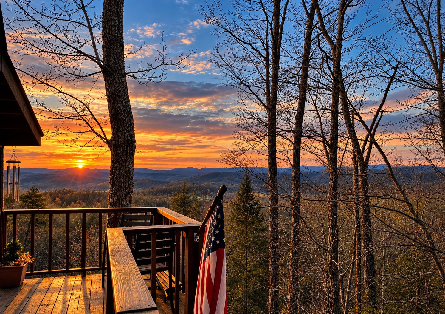 Une terrasse en bois ornée d’un drapeau américain, offrant une vue sur un paysage boisé au coucher du soleil.