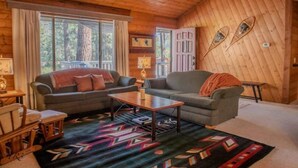 A cozy cabin interior with two sofas, a wooden coffee table, and a patterned rug. - Pinetree Place (Wrightwood)