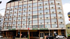 Ein mehrstöckiges Hotel mit zentralem Eingang, Klimaanlagen und einem Schild mit der Aufschrift 'HOTEL JARAGUA'.