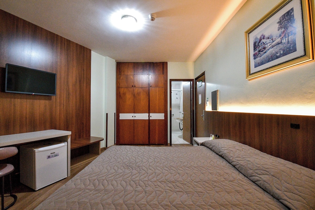Un dormitorio con cama, escritorio, televisión y armario.