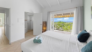 Une chambre d’hôtel avec un lit, une vue sur la mer et un balcon doté d’une balustrade.
