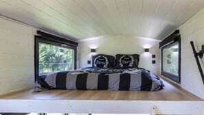 A compact bedroom with a bed, two bedside lamps, and large windows.