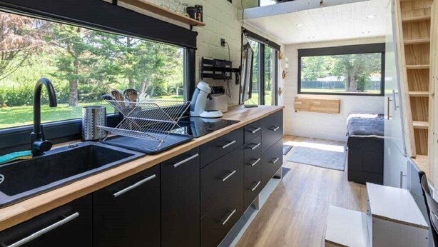 A modern kitchen with a large window, a sink, and a countertop with various appliances.