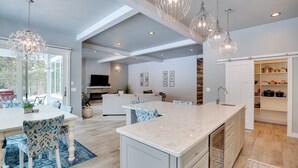 A modern kitchen with a large island, pendant lighting, and a view to the outdoors. - Modern Lead Cabin w/ Hot Tub, 6 Mi to Skiing! (Lead)
