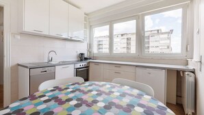 A compact kitchen with a window, white cabinets, and a polka dot tablecloth.