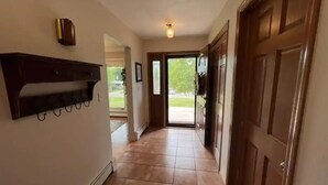 A hallway with a wooden door, a coat rack, and a light fixture on the ceiling. - Hidden oasis with northern feel (Cloquet)