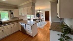 A kitchen with white cabinets, a central island, and a dining area with a chandelier. - Hidden oasis with northern feel (Cloquet)