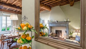 A dining area with a wooden table, chairs, a chandelier, and a mirror reflecting a fireplace and a window. - FRANTOIO a Romantic Farmhouse Apartment with Terrace and Views (Capannori)