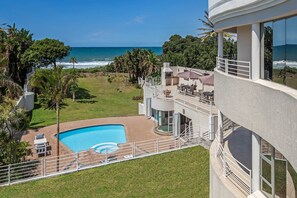 A modern building with a pool, outdoor seating, and a view of the ocean.