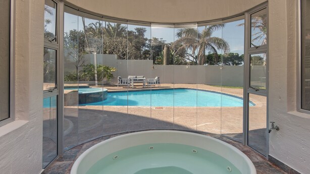 A spa area with a hot tub and a view of an outdoor swimming pool.