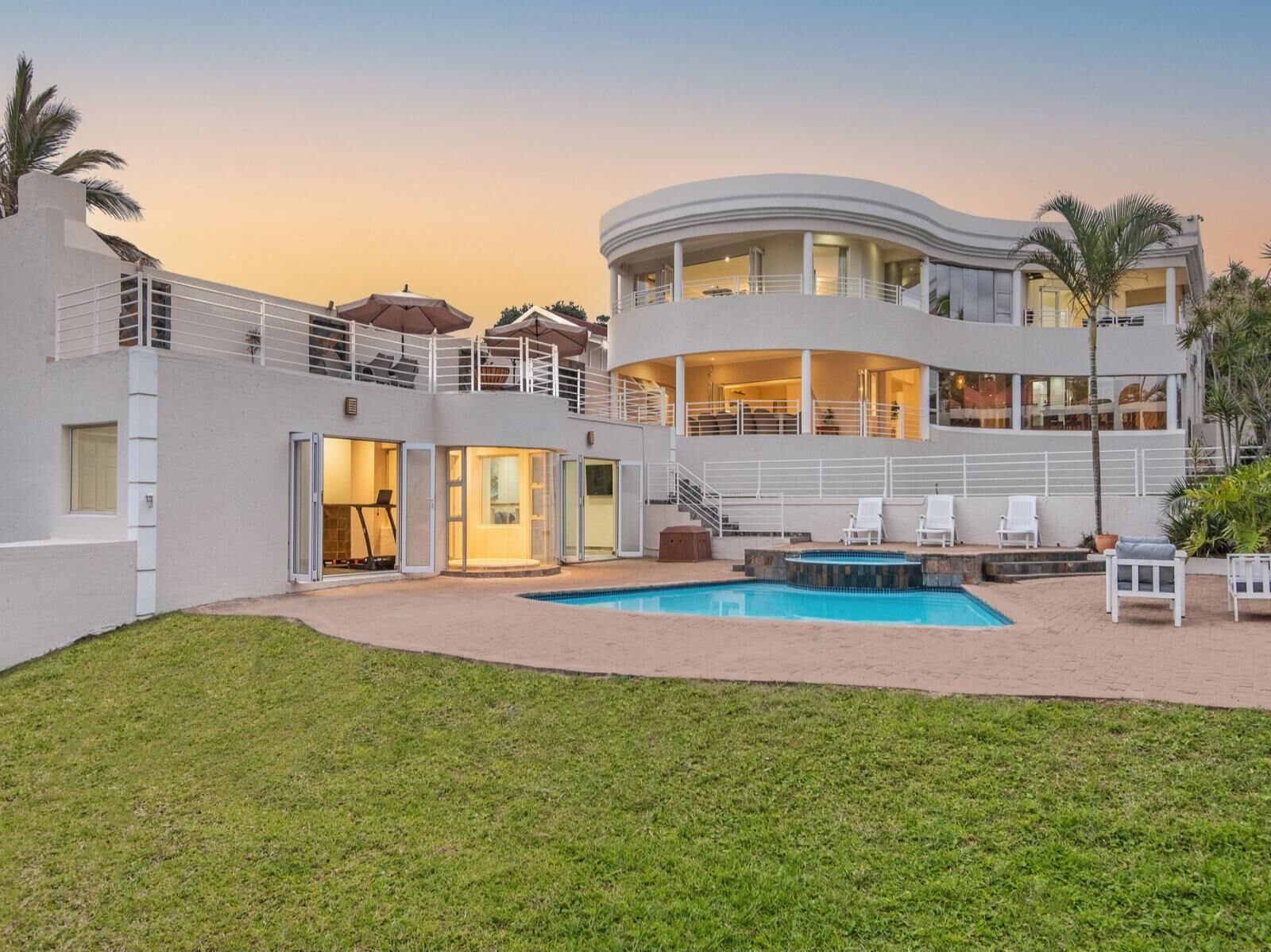 A modern multi-story building with a pool, outdoor seating, and a staircase leading to the upper levels.