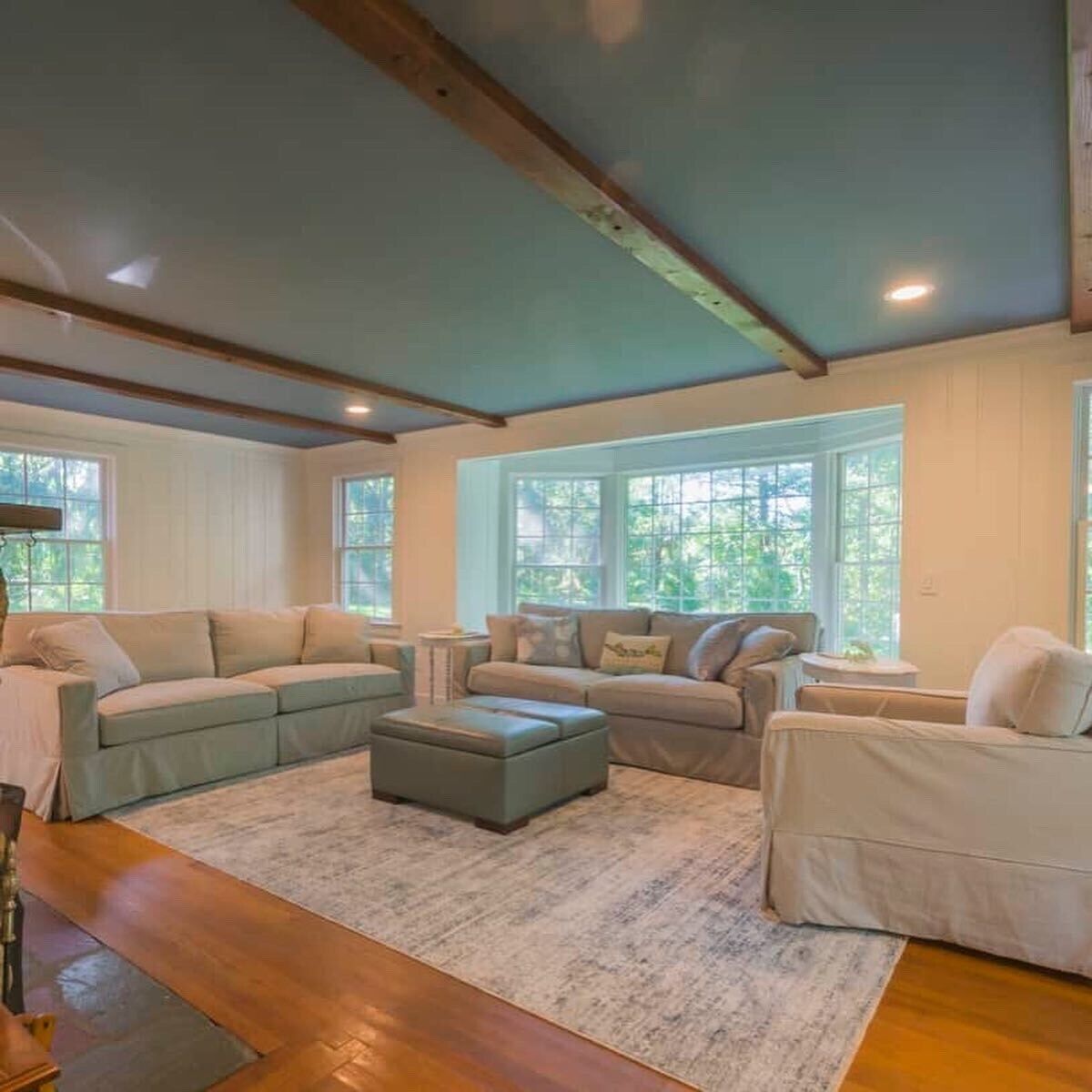 A spacious living room with a large sectional sofa, a small ottoman, and a wooden coffee table.