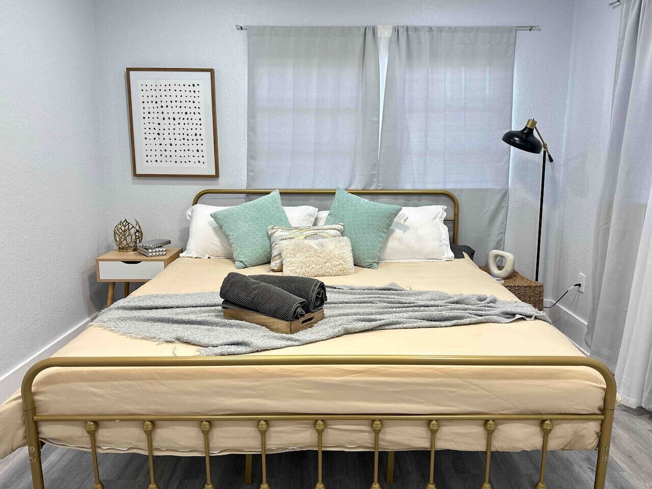 A neatly made bed with a beige headboard, a gray blanket, and multiple pillows in various colors.