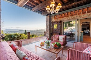 A cozy outdoor seating area with a view of distant mountains, a brick fireplace, and a modern interior.