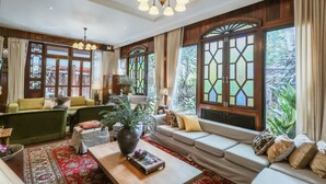 Ein geräumiges Wohnzimmer mit einer Sofagarnitur, einem Couchtisch und einem großen Fenster mit dekorativen Glasscheiben.