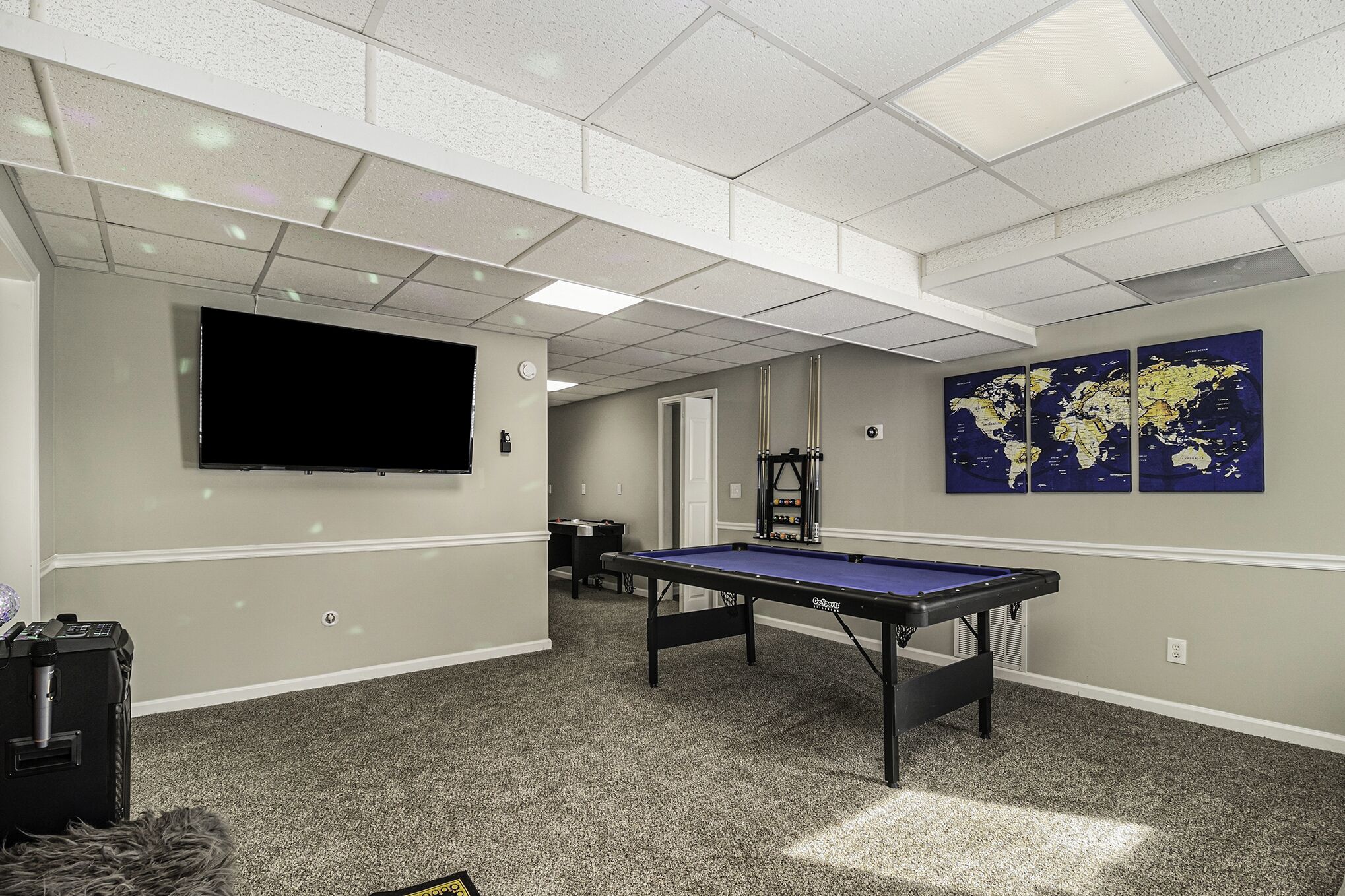 A room with a pool table, a flat-screen TV, and a world map on the wall.