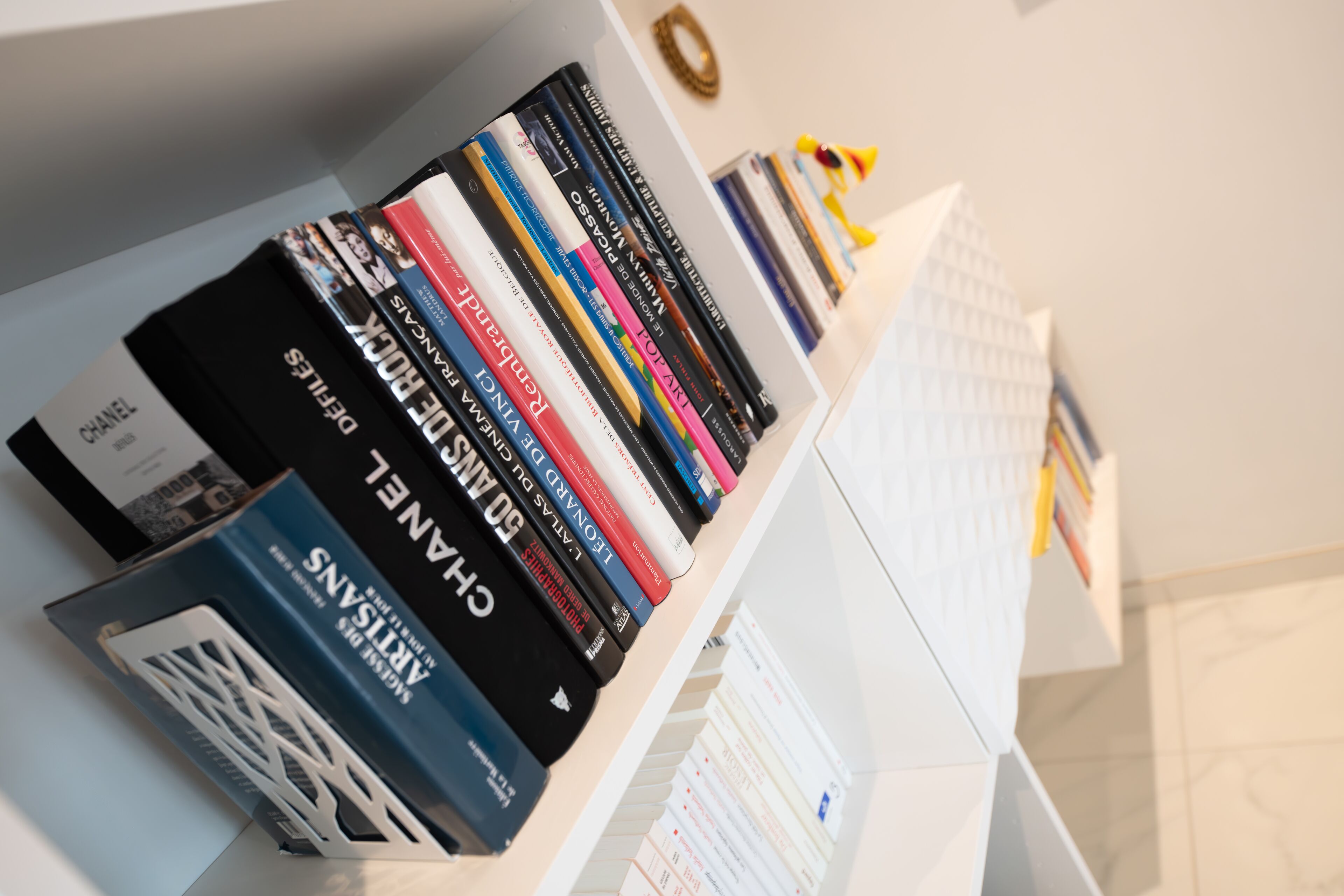 A bookshelf with various books and a few decorative items.