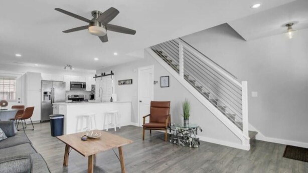 A modern living space with a kitchen, dining area, and a staircase.
