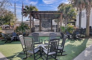 A gazebo with a welcome sign, outdoor seating with chairs and tables, and a flagpole with an American flag.