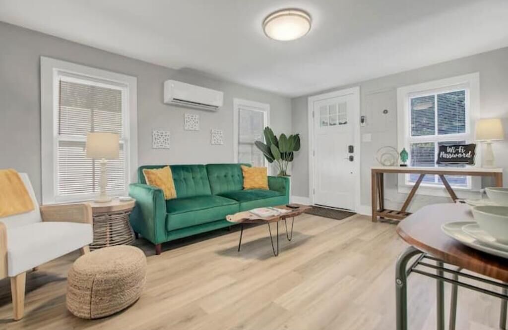 Una sala de estar moderna con un sofá verde, un sillón blanco y una mesa de centro de madera.