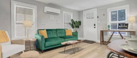 Una sala de estar moderna con un sofá verde, un sillón blanco y una mesa de centro de madera.