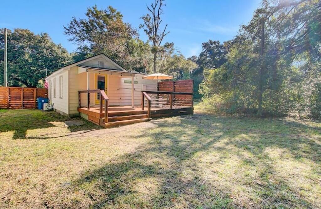 A small, single-story house with a porch and a wooden deck.