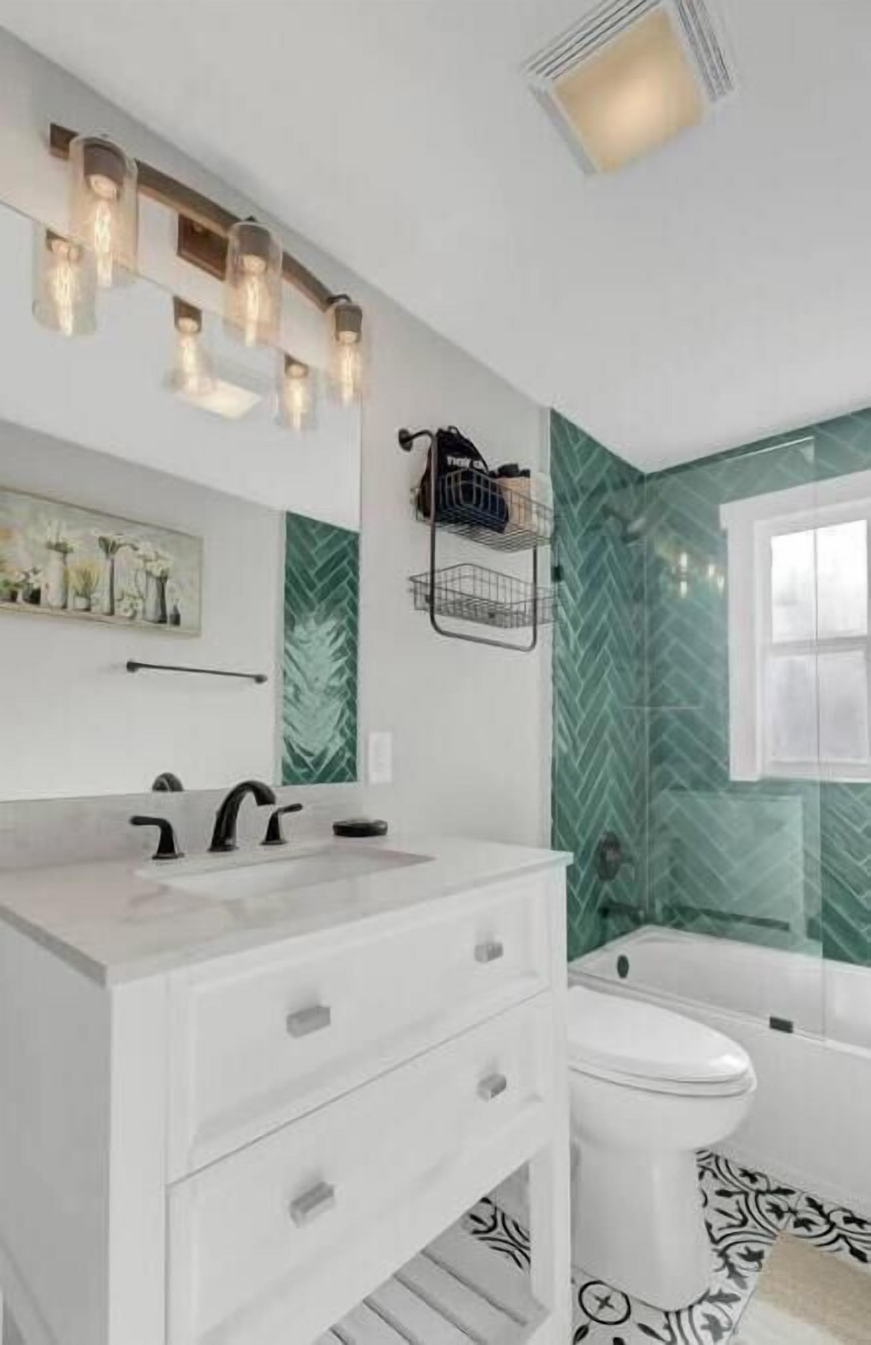 A bathroom with a white vanity, a mirror, and a green herringbone-patterned wall.